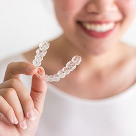 closeup of woman holding Invisalign aligner 