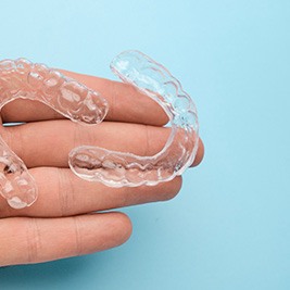 person holding two clear aligners