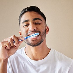Young man in white t-shirt brushing his teeth